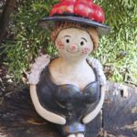 TF1002 Tonfigur Schwarzw&auml;lderin sitzend mit rotem Bollenhut