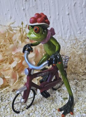 Glücksfrosch Fahrradfahrer mit rotem Fahrrad und großem Bollenhut